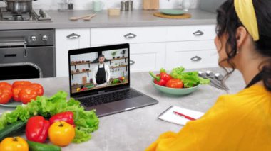 Woman in home kitchen greets study online video call webcam laptop listen teacher. Man chef food blogger in computer screen tells recipe of dish teaches housewife remote cooking culinary lesson course