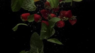 Yavaş çekim karışık çilek, limon, elma ve nane arkaplanda şeffaf suya dökülüyor. Taze böğürtlen ve akvaryuma sıçrayan meyveler. Sağlıklı yemek, diyet, hava kabarcıkları