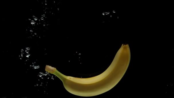 Медленное Движение Один Банан Падает Прозрачную Воду Черном Фоне Брызги — стоковое видео
