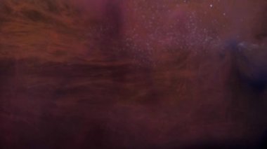 Yavaş hareket eden turuncu ve pembe mürekkep akriliği suda karışıyor, suyun altında yavaşça dönüyor. Akvaryumdaki akrilik bulut boyası. Soyut duman patlaması animasyonu. Şeffaf suyun altında yüzen hava kabarcıkları