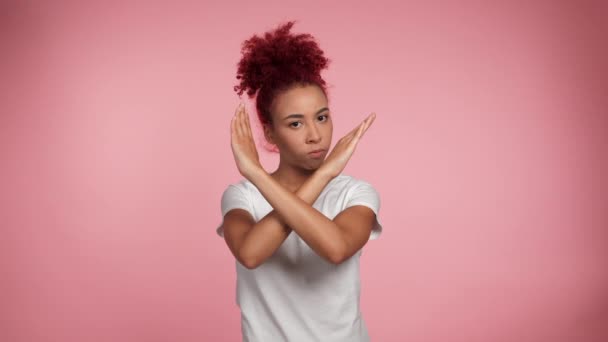肖像画深刻なアフリカ系アメリカ人の赤毛の巻き女性は手を横断ジェスチャーを示すカメラを見て停止します 白いTシャツの女性は決して表現しません 私はピンクの背景にそれを署名する必要はありません — ストック動画