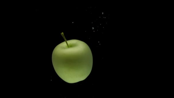 Slow Motion One Green Apple Spinning Falling Transparent Water Black — стоковое видео