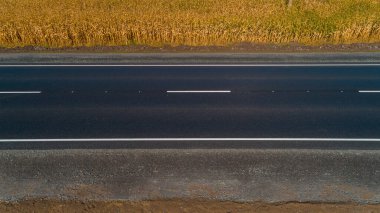 Drone hava manzaralı yeni asfalt yolu Yazın güneşli bir günde buğday tarlasının yanında