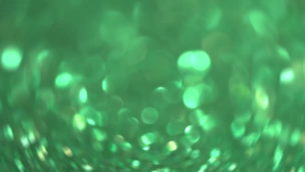 緑のグリッターの背景 ライトボケ魔法のクリスマスライト 光沢のある質感 休日の光 飛行粒子は美しいボケを形成します 輝くクリスマスの背景 高品質4K映像 — ストック動画