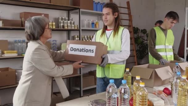 Седовласая Пожилая Азиатка Принимает Коробку Пожертвований Молодого Волонтера Высококачественные Кадры — стоковое видео