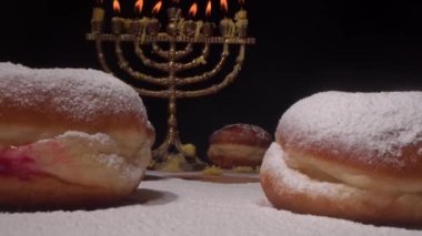 Yahudi ailesi Hanukkah 'ı kutlar ve Sufganiyot çörekleri yer, İsrail çörekleri. Menorah 'ın yanan mumlarının ışıkları. Yüksek kalite 4k görüntü