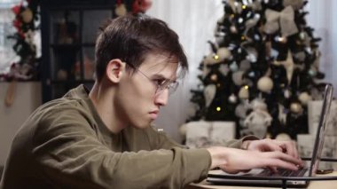 Genç bir adam Noel tatilinde evde bilgisayarın başında çok çalışır. Yüksek kalite 4k görüntü