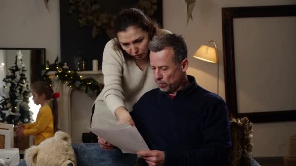 子供が税金 住宅ローン ローン ユーティリティ請求書を持つ紙文書を見ている悲しい中年のカップル クリスマス休暇中の危機 高品質の4K映像 — ストック動画