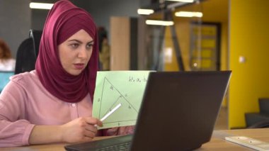 Uzaktan çalışan Müslüman kadın öğretmen. Bilgisayarı, webcam 'i ve matematik dersini kullanan öğrencilerle çevrimiçi sohbet. Uzaktan öğrenme, uzaktan çalışma, serbest çalışma. Yüksek kaliteli FullHD görüntüler