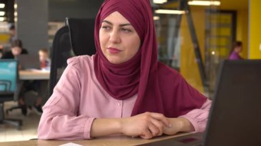 Ofisteki üzgün Müslüman kadın. Baş ağrısı, stres, teslim tarihi ve aşırı çalışma. Anksiyete, akıl sağlığı ve masa başında çalışanlardan bıkkınlık, yorgunluk, yorgunluk ve yorgunluk.. 