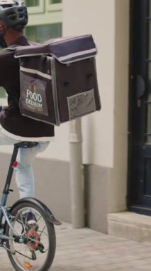 Dikey video: Servis elemanı müşteriye öğle yemeği siparişi veriyor, erkek kadına restoran yemeğiyle birlikte kağıt torba veriyor. Gülümseyen Afro-Amerikan müşteri hazır yemek alıyor.