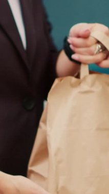 Dikey video: Paket paket kurye müşteriye yiyecek siparişi veriyor, Ukala ve NFC 'yi kullanarak podyumlardaki yemeği ödüyor. Restoran işçisi fast food servisi, yemek teslimatı. El bilgisayarı