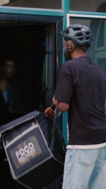 Dikey video: Müşteri fast food servis kuryesine bağırıyor, taşıyıcı ön kapıdaki öfkeli müşteriye yanlış yemek siparişi veriyor. Öfkeli müşteri yemek konusunda düşüncesiz ve tatminsiz davranıyor.