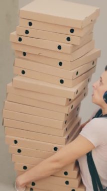 Dikey video: Sakar yemek kuryesi düşen pizza kutularını yakalamaya çalışıyor, fast food servisini düşürdükten sonra korkmuş ve müşteri kapısından kaçıyormuş gibi yapıyor. Kötü hizmet veren bir taşıyıcı.