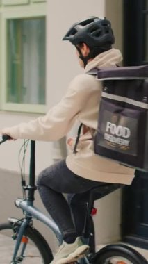 Dikey video: Fast food dağıtım elemanı Afro-Amerikan kadınına paket olarak yemek siparişi veriyor, ön kapıya kağıt torba getiriyor. Kadın kurye hazır yemek, hızlı yemek.