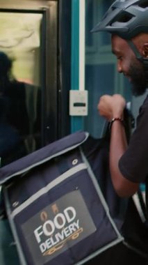 Dikey video: Yemek dağıtım elemanı müşteriye kese kağıdında yiyecek veriyor, müşteri NFC ile birlikte smartwach kullanarak sipariş veriyor. Erkek kurye öğle yemeği getiriyor, ödeme yok. El kamerasıyla.