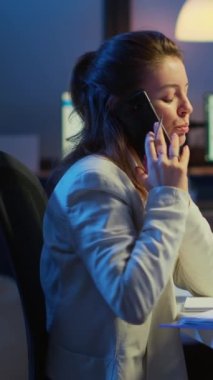 Dikey video: Sinir bozucu yönetici, gece geç saatlerde iş yerinde mesai yapan çalışanla telefonda tartışıyor ve mali sorunları çözüyordu. Modern kullanım ile meşgul çalışan