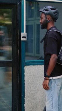 Dikey video: Gülümseyen kurye müşteriye fast food siparişi veren kağıt torba veriyor, ön kapıda ofis yemeği dağıtım hizmeti veriyor. Kadın, restorandan yemek alıyor, müşteriler yemek yiyor.