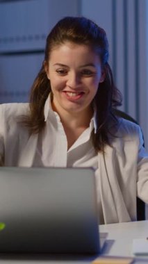 Dikey video: Happy Freelancer şirket ofisinde fazla mesai yaparak dizüstü bilgisayarından iyi haberler alıyor. Modern teknoloji ağını kullanan hevesli bir çalışan. Fazla mesai yapan bir yazar.