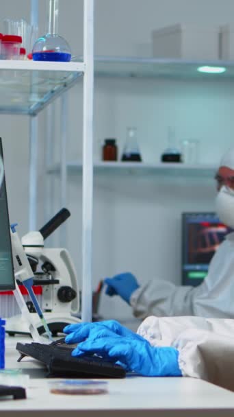 垂直录像 身穿防护服的科学家在配备了化学品的实验室工作 利用高科技和技术研究如何治疗疫苗进化的生物学家小组 — 图库视频影像