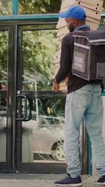 Dikey video: Sakar restoran kuryesi müşterinin önüne pizza kutularını bırakıyor, şok olmuş müşteri pizza paketleri siparişini yakalıyor. Erkek kurye özür diliyor, kötü yemek servisi var.