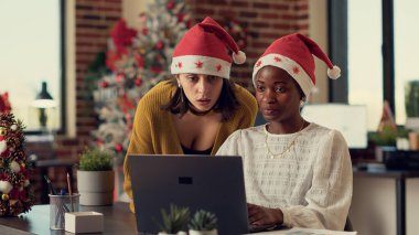 Mevsimsel süslemeler ve dekorasyonlarla ofiste beyin fırtınası yapan çeşitli meslekdaşlar. Çalışanlar noel tatilinde bilgisayardaki verilerle takım çalışması yapıyorlar..