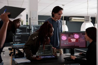 Bilgisayar ekranında güvenlik ihlali uyarısı alan çok ırklı programcılar hackleme ve kritik hatayı çözmeye çalışıyorlar. Mühendisler terminal penceresi kullanıyor ve sistem çökmesini engelliyor.