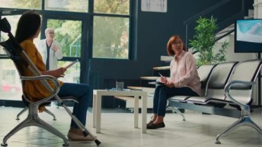 Bekleme salonunda tıbbi kontrol raporu yazan yaşlı Asyalı hasta, randevu formlarını doldurmasına yardım eden hemşire. Uzmanla muayeneye hazırlanıyorum. Üçayak atışı.