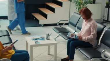 Asyalı bir hastanın sağlık kontrolünden geçerken portresi. Hastane kliniğinin bekleme salonunda oturuyor. Tıbbi randevusu olan bir kadın sağlık merkezinde muayeneye hazırlanıyor..