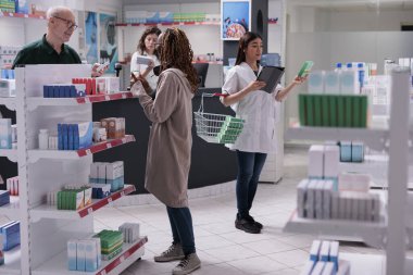 Eczanedeki eski müşterilerle kardiyoloji ilaçlarının reçetesi hakkında konuşuyorlar. Müşteriler hap, takviye, vitamin alıyor. Sağlık desteği