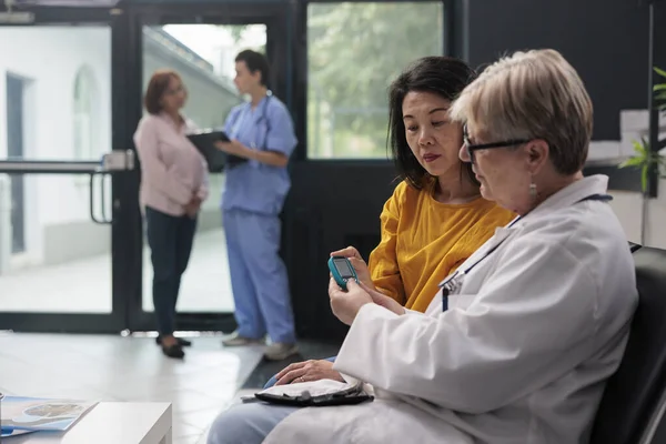 의사는 이시아인 환자와 미터를 가지고 상담하면서 샘플에서 인슐린 포도당 수치를 — 스톡 사진