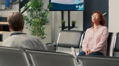 Asyalı bir kadın, reçeteli ilaç ve tedavi görmek için uzman doktorla tıbbi randevuya gitmek üzere lobide bekliyor. Hastanedeki kıdemli kişi..