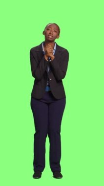 Dikey video: Afro-Amerikan şirket çalışanı sessizce dua ediyor, yeşil ekranda dua ediyor. Ruhsal meditasyon yapan dindar, umutlu bir kadın dileğini yerine getirmek istiyor.
