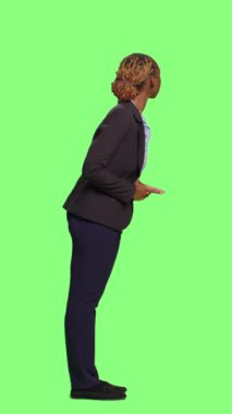 Dikey video: Takım elbiseli bir şirket yöneticisi yeşil ekran fon kuyruğunda bekliyor, tüm gövde yeşil ekran. Şirket çalışanı arka planda duruyor ve hazırlanıyor. Meraklı sabırsız bekleyin..