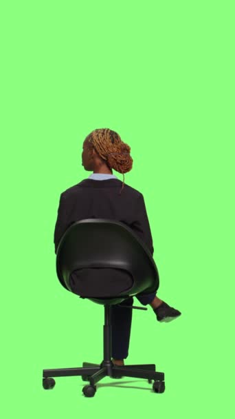 垂直视频 办公室经理坐在椅子上 在工作室等着 全身上下都是绿色屏幕背景 穿着西服的年轻女商人等着 坐着准备迎接 绿屏背景 — 图库视频影像