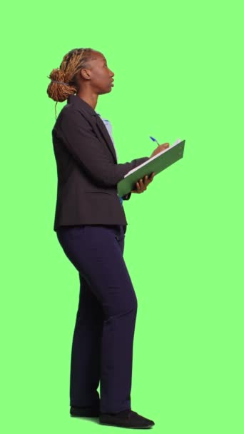 垂直视频 公司员工在绿屏背景下的文件上做笔记 在剪贴板上写信息和公司数据 作为经理工作的妇女的全身绿色屏幕 — 图库视频影像