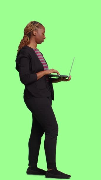 垂直视频 年轻微笑的女性在笔记本电脑上浏览互联网 使用无线Pc浏览在线网站 快乐的现代女孩站在全身上下绿屏的背景上 社交媒体 — 图库视频影像