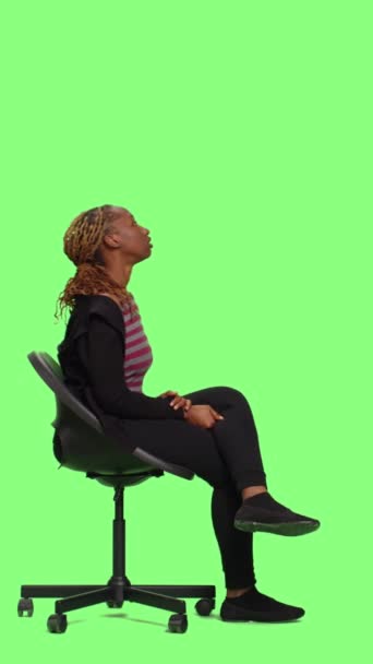 Dikey Video Sandalyede Oturan Yeşil Ekranda Poz Veren Genç Kişi — Stok video