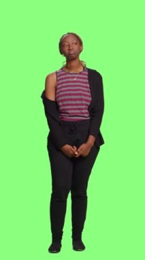 Dikey video: Sabırsız model yeşil ekran arkaplanı üzerinde yeşil ekran arkaplanı üzerinde bekliyor. Genç, neşeli kız bekle ve meraklı, modern, kendine güvenen yetişkin kadın rolü yap..