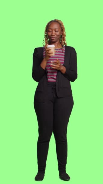 縦型ビデオ フルボディのグリーンスクリーンを背景にコーヒー飲料の笑顔モデル飲料カップ 緑の画面の上に立って隔離された背景とカフェインを楽しんでいます カジュアルなドリンクをお楽しみください — ストック動画