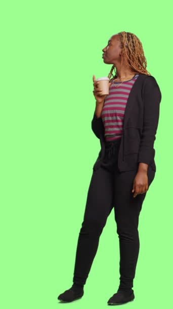 垂直视频 年轻女性在绿屏背景下享用一杯咖啡饮料 站在绿屏上 喝咖啡因 随便喝点什么 — 图库视频影像
