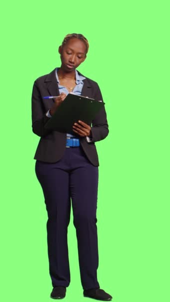垂直视频 企业会计在绿屏背景下的文件上做笔记 在剪贴板上写信息和公司数据 作为经理工作的妇女的全身绿色屏幕 — 图库视频影像