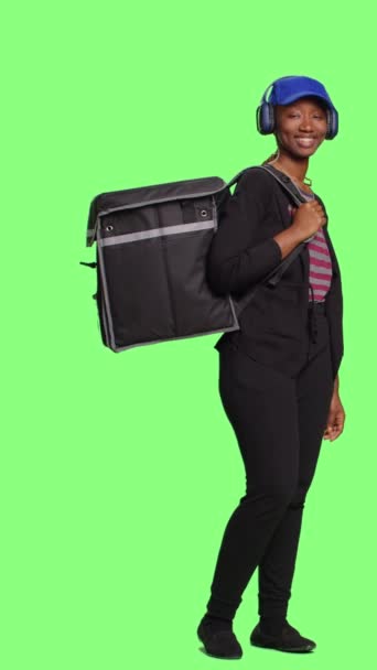 垂直录像 非洲裔美国女信使背着热背包 在绿色屏幕背景下运送食物 以袋装 全身绿屏为背景的速食食品女服务员 — 图库视频影像