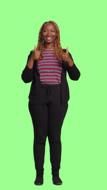 垂直视频 在绿屏背景上的女性展示大拇指向上和认可的标志 做的动作就像站在全身覆盖背景的姿势 演播室里好的正面和好的乐观象征 — 图库视频影像