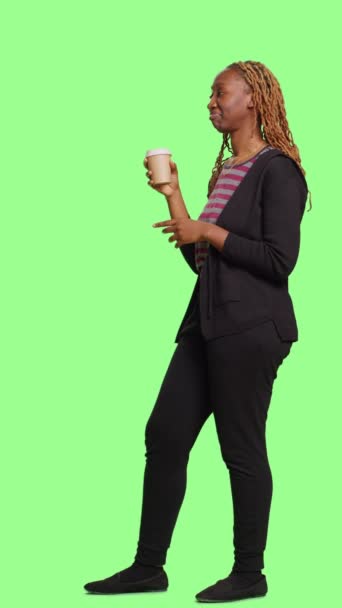 垂直ビデオ コーヒーカップドリンクをフルボディグリーンのスクリーンバックで提供している幸せな人は 緑の画面の孤立した背景の上に立って カフェイン飲料を飲みます カジュアルなリフレッシュをお楽しみください — ストック動画