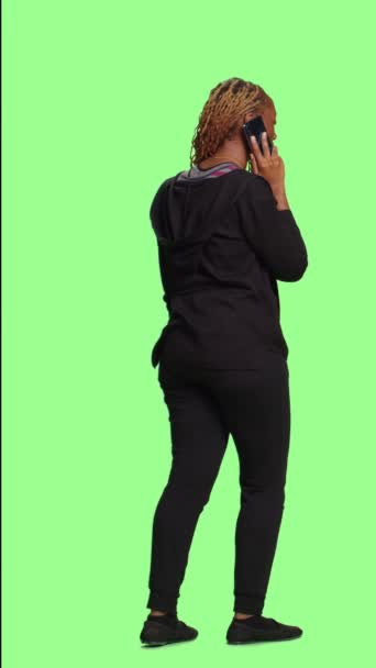 垂直视频 非洲裔美国妇女在绿屏背景下通过电话交谈 使用的是在孤立的背景下全身而退的智能手机线路 在演播室里拿手机的成年人 — 图库视频影像