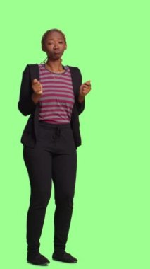 Dikey video: Mutlu komik kız stüdyodaki tüm yeşil ekran arka planında dans hareketleriyle oynaşıyor. Aptal aktif yetişkin yeşil ekranda dans ederken eğleniyor, kendinden emin manken..