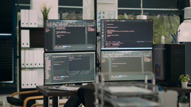 Boş büro masasında veri algoritmaları derleyen bilgisayarlarla parola görüntüleme monitörleri. Temrinal pencere üzerindeki html betiği ile yapay zeka sunucuları bulut hesaplama.
