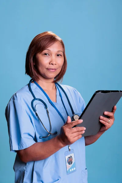 Starsza Pielęgniarka Posiadająca Urządzenie Cyfrowe Sprawdza Ubezpieczenie Zdrowotne Przed Rozpoczęciem — Zdjęcie stockowe