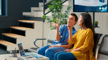 Kadın hemşire ve Asyalı hasta, bekleme odasında gelişmiş gerçeklik ve holografik görüntü kullanarak fütüristik holograma bakıyorlar. Kontrol sırasında yüksek teknoloji 3D ai analiz ediliyor.